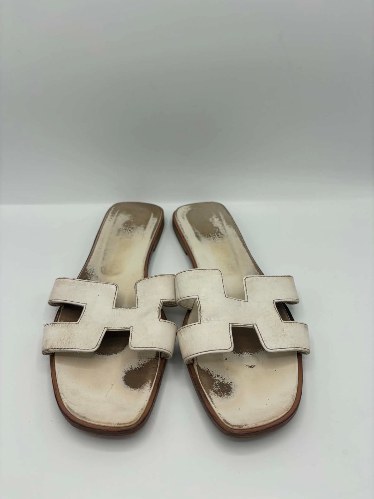 Sandales Hermès Oran blanches avant les soins dans notre atelier