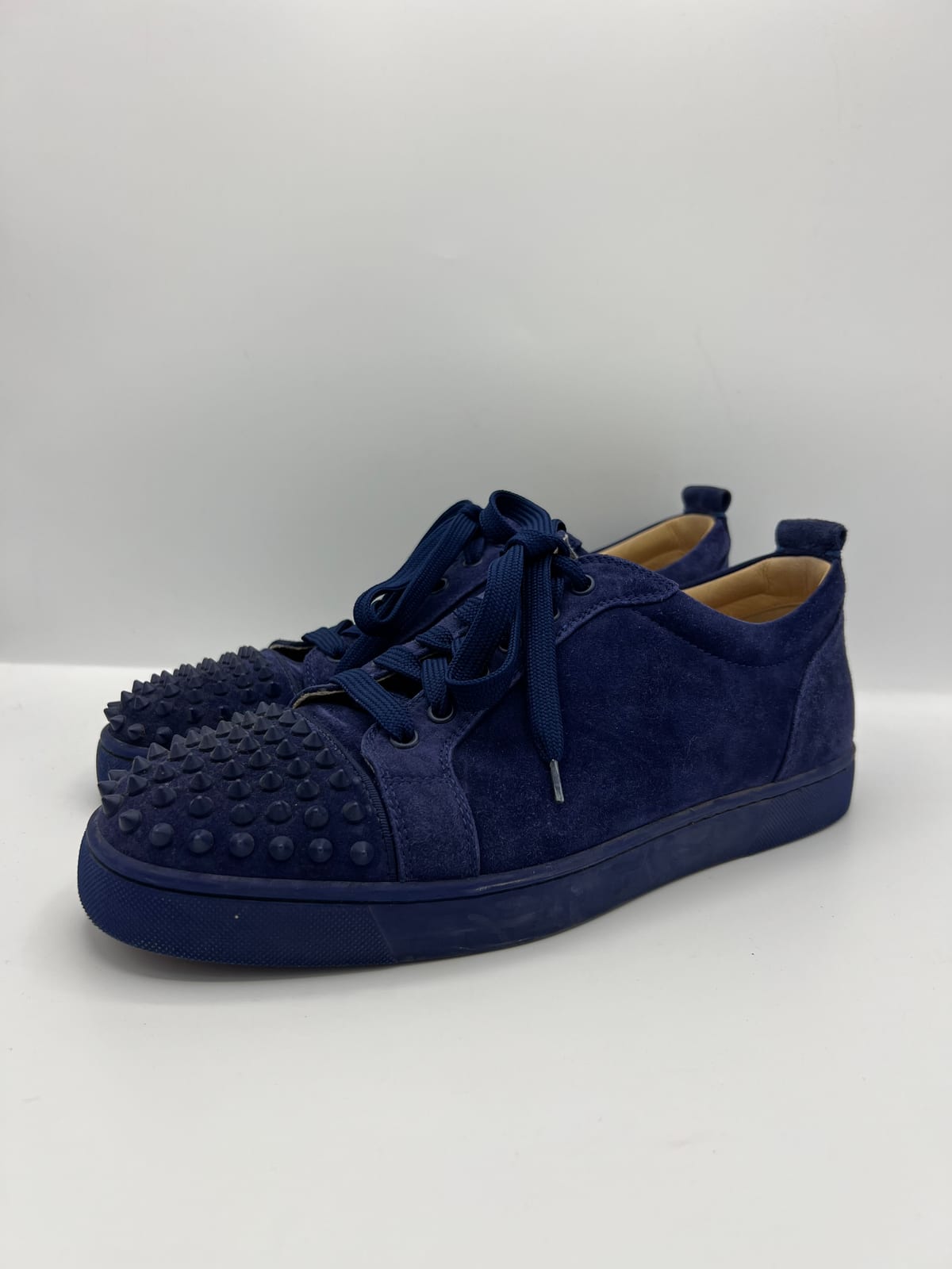 Sneakers Louboutin en daim bleu à clous avant les soins dans notre atelier